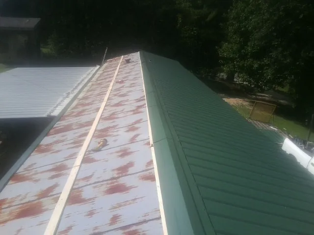 Old rusted panels beside newly installed green metal roofing — Wind Damage Roof Repair by Roofing Brothers in Florham Park