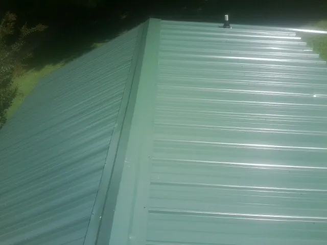 New green metal panels meeting at the ridge of a roof — Flat Roof Repair work by our crew in Florham Park