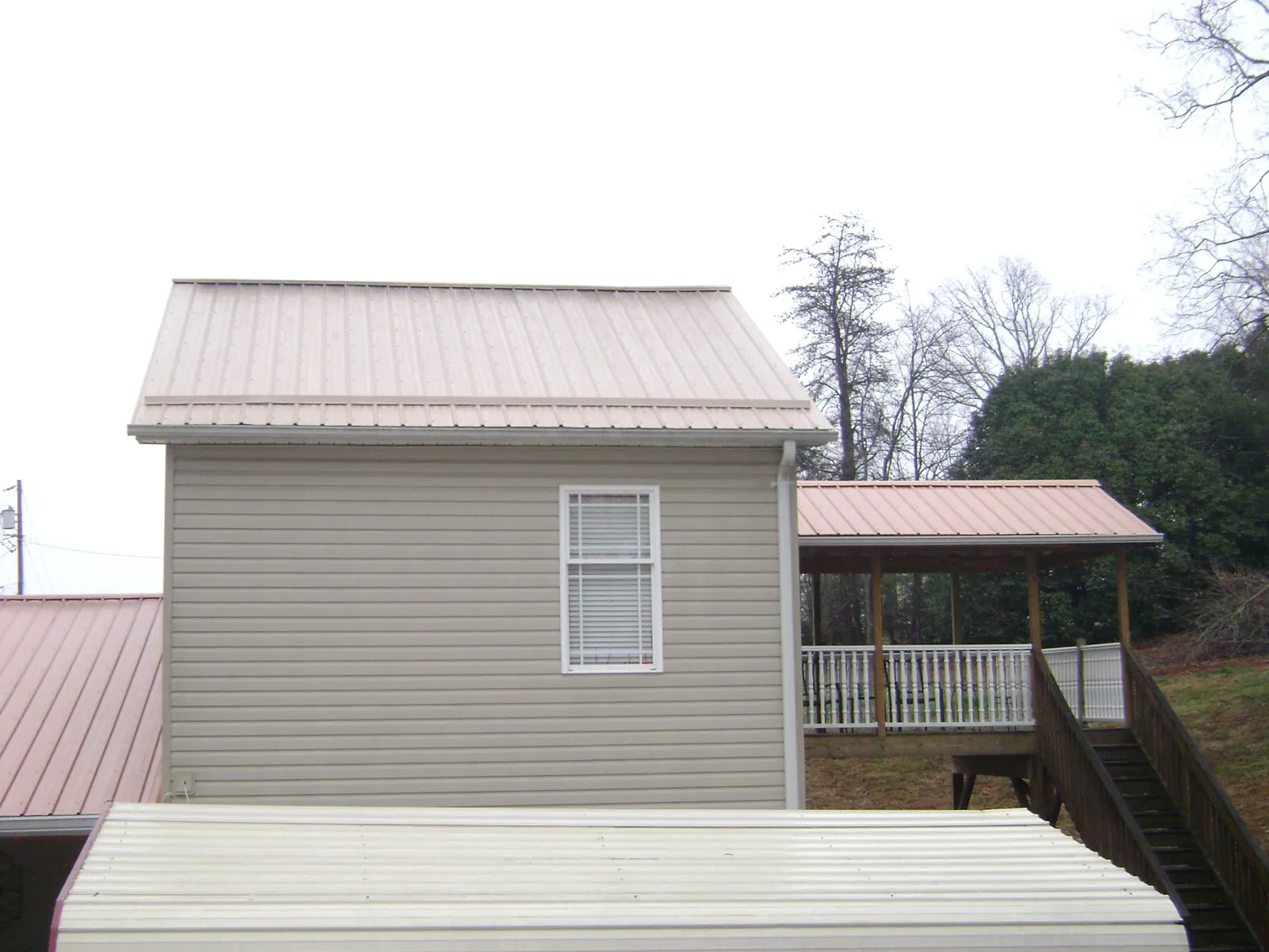 Tan metal roofs on a two story addition and attached porch, from a Roof Replacement job in Florham Park