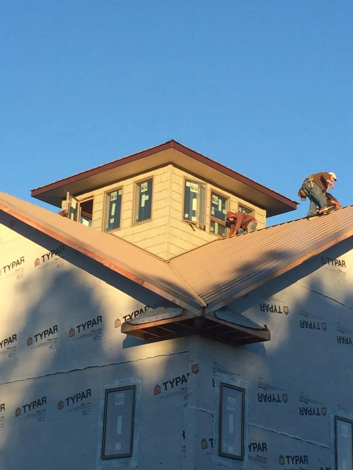 Roofers working around a rooftop cupola on a new metal roof at sunset — Roof Waterproofing in Florham Park by Roofing Brothers